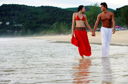 情侣肩并肩沿着海滩散步