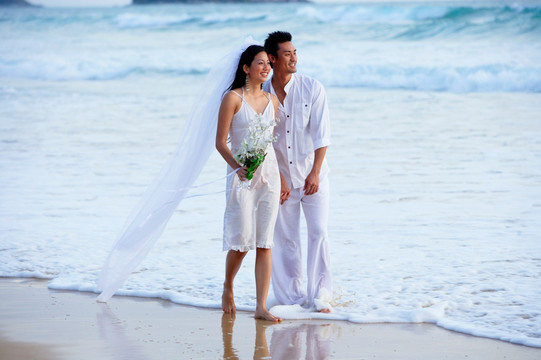 新娘和新郎在海滩上散步