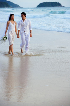 新娘和新郎在海滩上散步