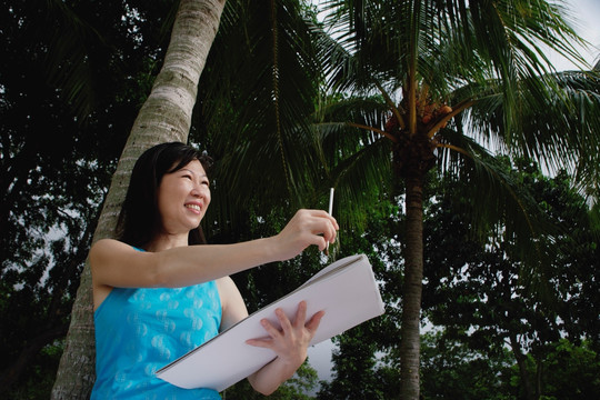 速写本站在一棵椰子树下的女人