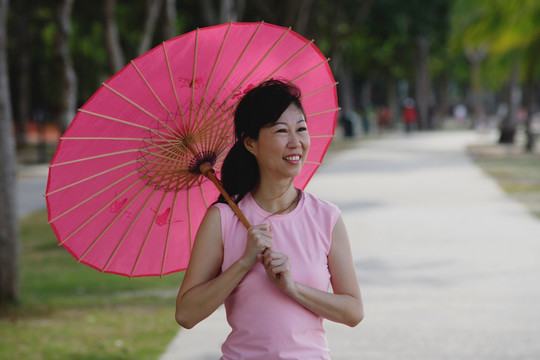 使用粉红色雨伞的成熟女人