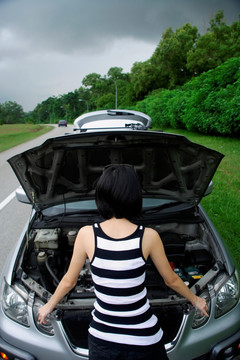 一个女人在汽车的引擎盖下检查