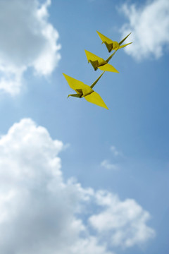 3个黄色纸鹤反对天空背景