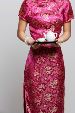 女人穿着粉色旗袍捧茶