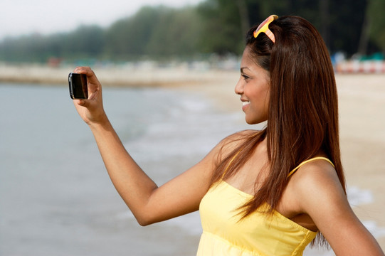 在海边使用手机自拍的女人