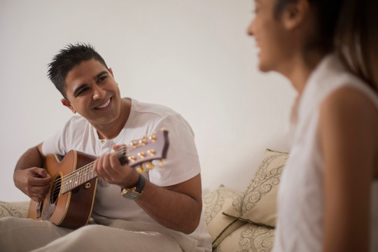 男人微笑着为女人弹吉他