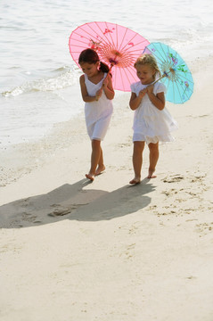 撑伞在海滩上行走的女孩