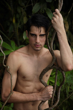 年轻人倚在丛林藤蔓上