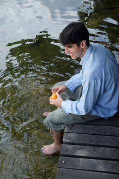 年轻人有橙色，脚悬在湖中