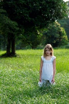 在草地上穿着白色连衣裙的少女