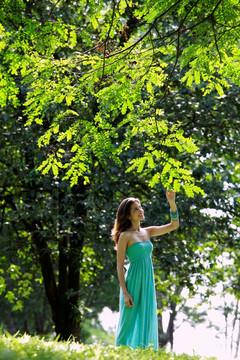 年轻女子触摸树叶的树