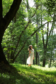 年轻女子穿着白衣在树林中行走