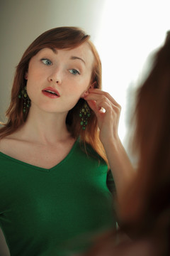 年轻女子试图在镜子耳环