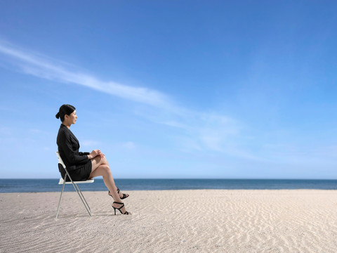 坐在椅子上看着海滩的女人