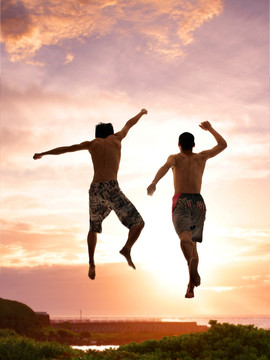 在海边跳跃的两个男人