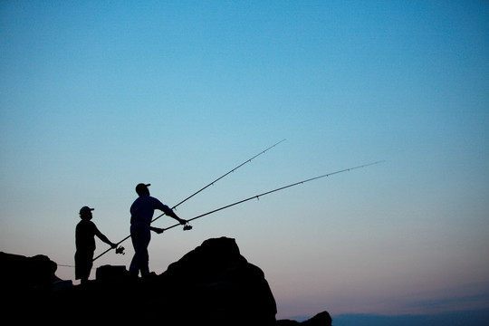 站在岩石上钓鱼的两人