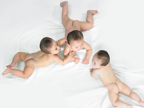 趴在床上的三个婴儿