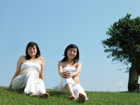 坐在草坪上的两名孕妇