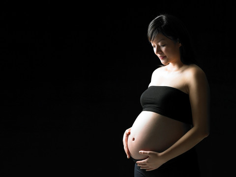 微笑的孕婦雙手放在肚子上