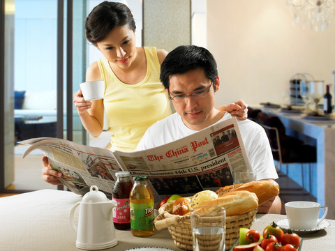 在吃早餐看报纸的夫妇