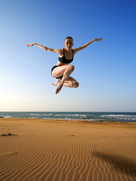 在海边展开双臂跳跃的女人