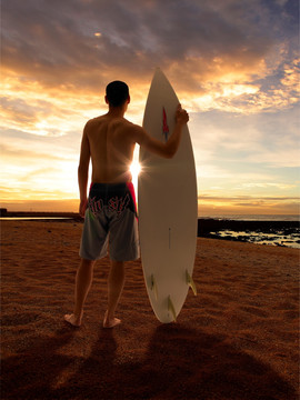 拿着冲浪板的男人站在沙滩上