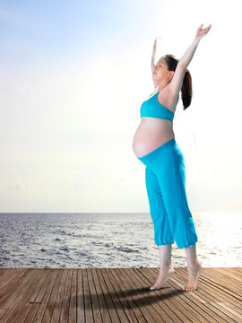站在甲板上举起双臂的孕妇