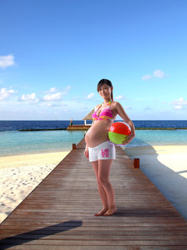 站在甲板上拿着沙滩球的孕妇