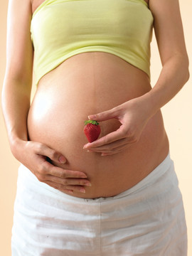 拿着一颗草莓的孕妇
