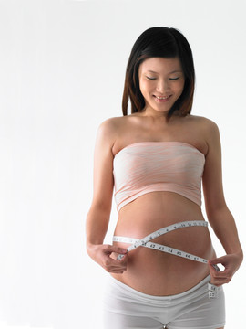 在用皮尺测量肚子的孕妇
