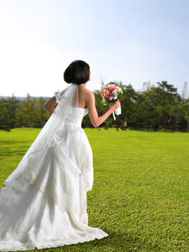 拿着鲜花在公园里奔跑的新娘