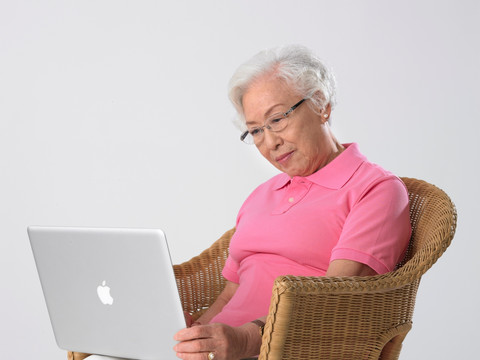 坐在藤椅上使用笔记本电脑的女人