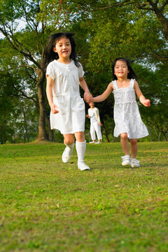 走在公园草坪上的两个小女孩