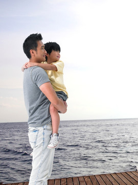 抱着儿子看着大海的父亲
