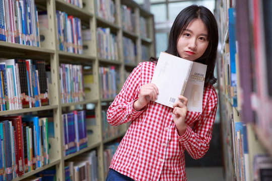 在大学图书馆里拿着书本的女学生