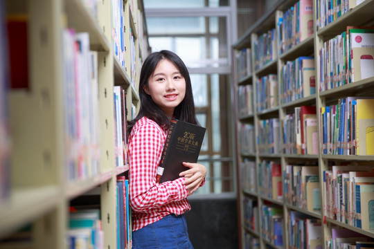 微笑的女学生拿着一本书籍