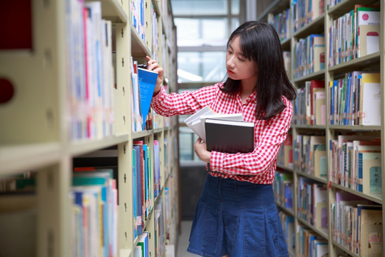 在大学图书馆里挑选书的女大学生