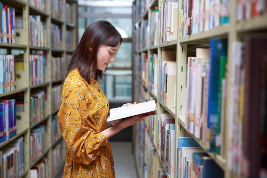 站在大学图书馆里认真看书的女学生