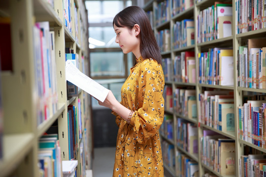 站在图书架前看书的女大学生