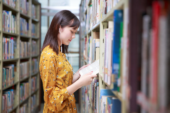 在图书馆戴着耳机看书的女学生