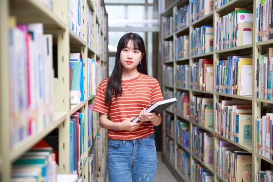 在图书馆里拿着书的女学生