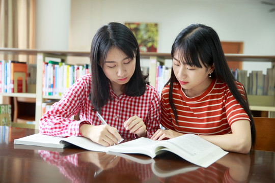 坐在图书馆里讨论作业的女学生们