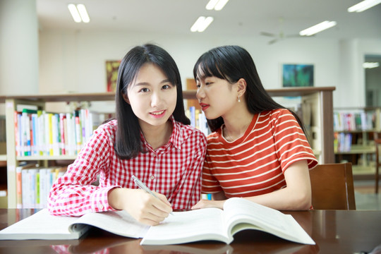 女学生们坐在图书馆里小声交谈着