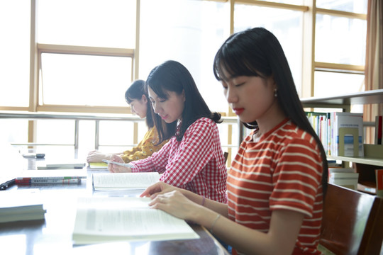 女学生们坐在图书馆里看着书