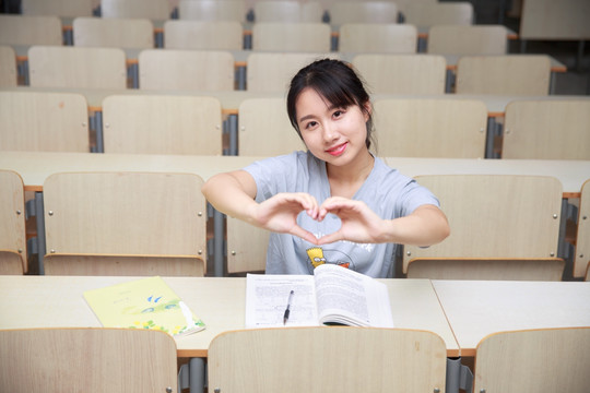 微笑着做着爱心手势的女学生