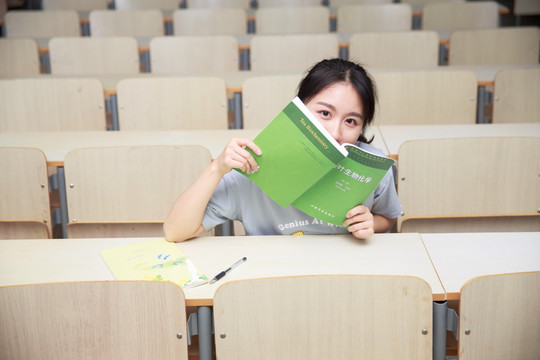 拿着书本的女学生坐在大学教室里