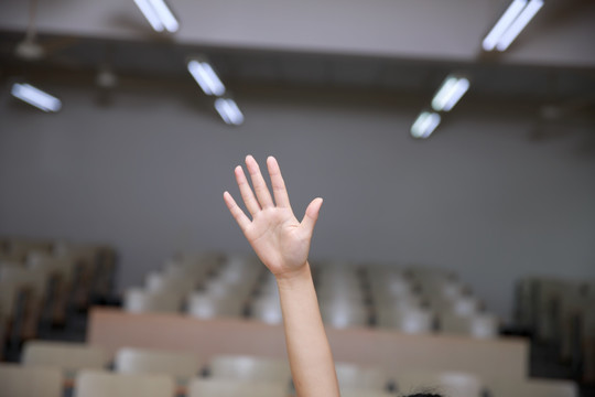 在大学教室里举起手的女大学生