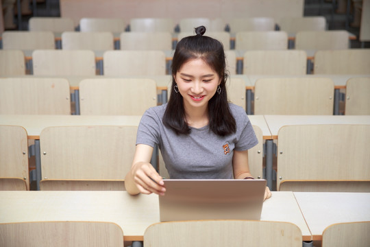 在大学教室里看着电脑屏幕的女学生