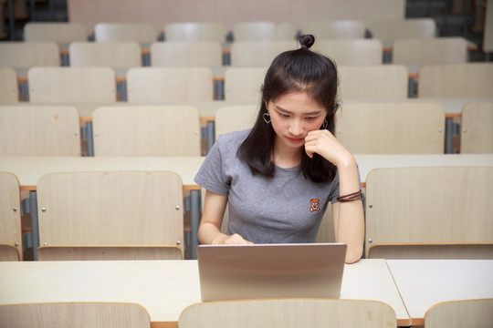 在大学教室里使用笔记本电脑的女学生