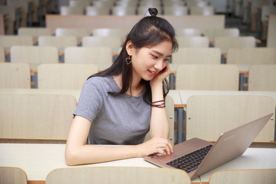 在大学教室里用笔记本电脑的女学生